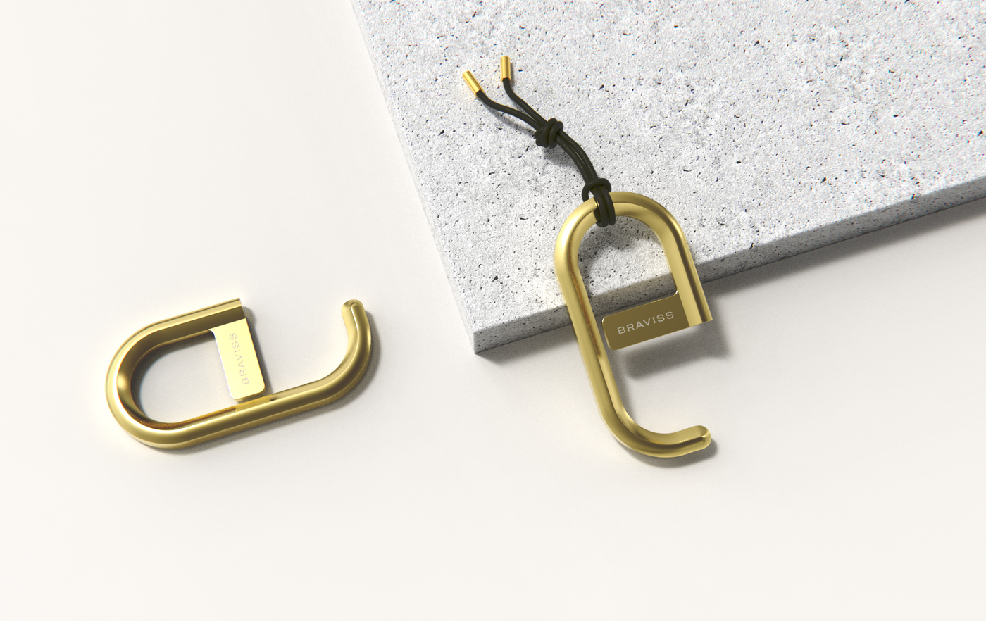 Picture of two BRAVISS brass keychain touch tool shot from the top. One product is laying flat on the left next to a marble textured stone slab. On top of lay another brass keychain touch tool with leather fob string tied to its top.